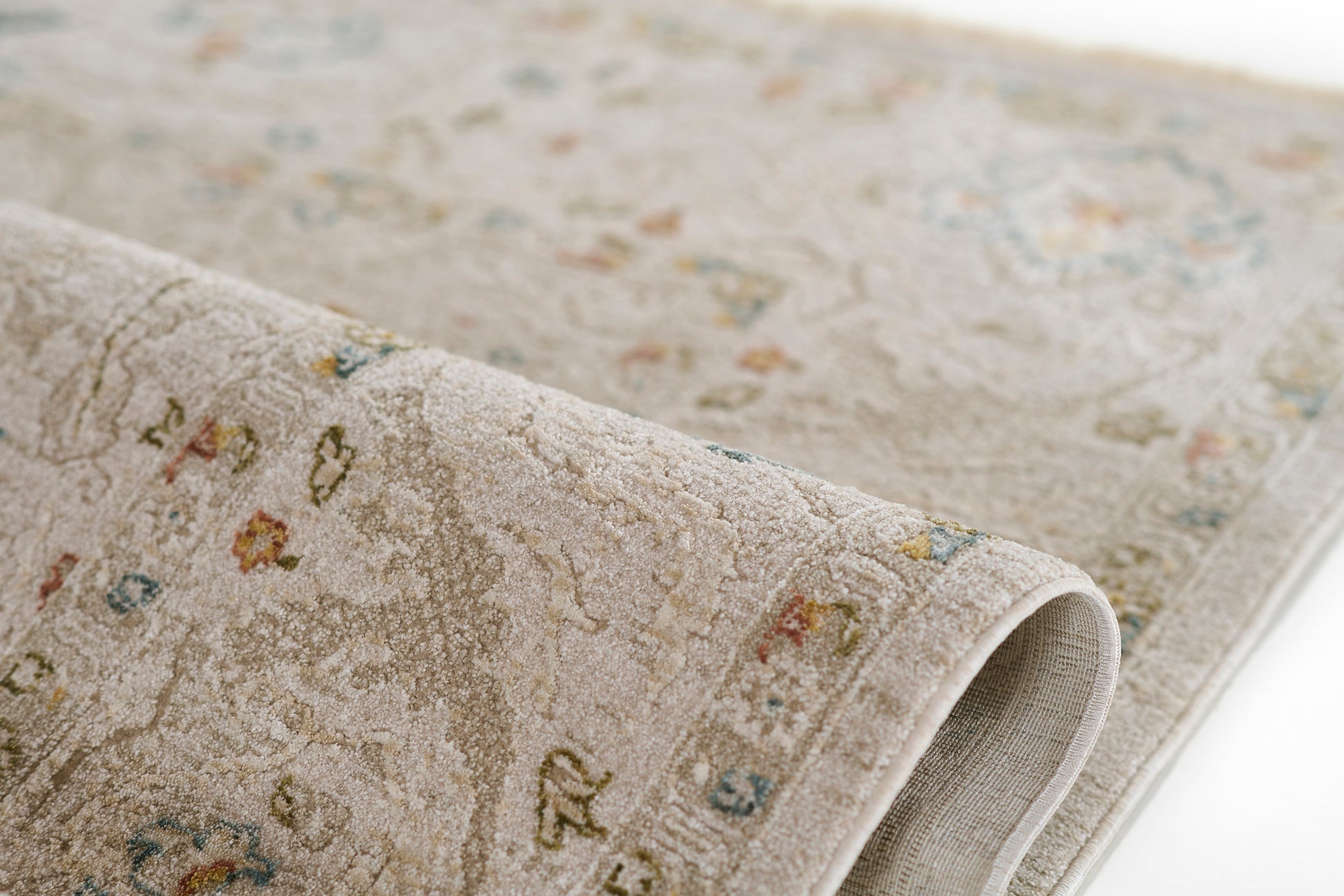 Beige vintage-style rectangular oriental rug with subtle floral motifs in blue, green, red and yellow; plush textured pile.