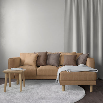 Beige solid fabric upholstery on an L-shaped sofa with taupe cushions and chaise, wooden legs, round wooden coffee table and soft rug.