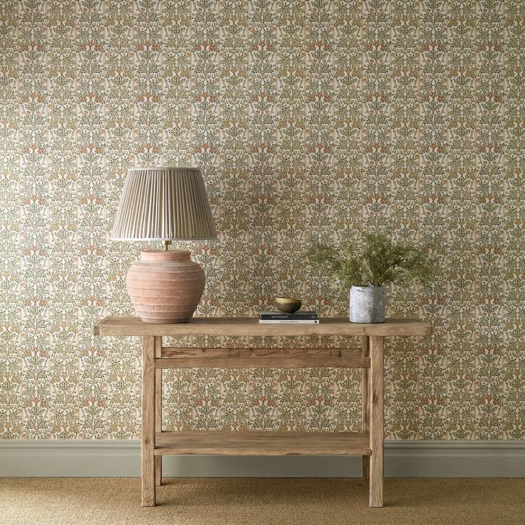 Morris & Co “Oak & Blossom” wallpaper (pattern MUNW217589) in Chestnut & Primrose, showing oak leaves, acorns, and delicate blossoms over subtle striped background — a vintage botanical heritage design for elegant, classic interiors.