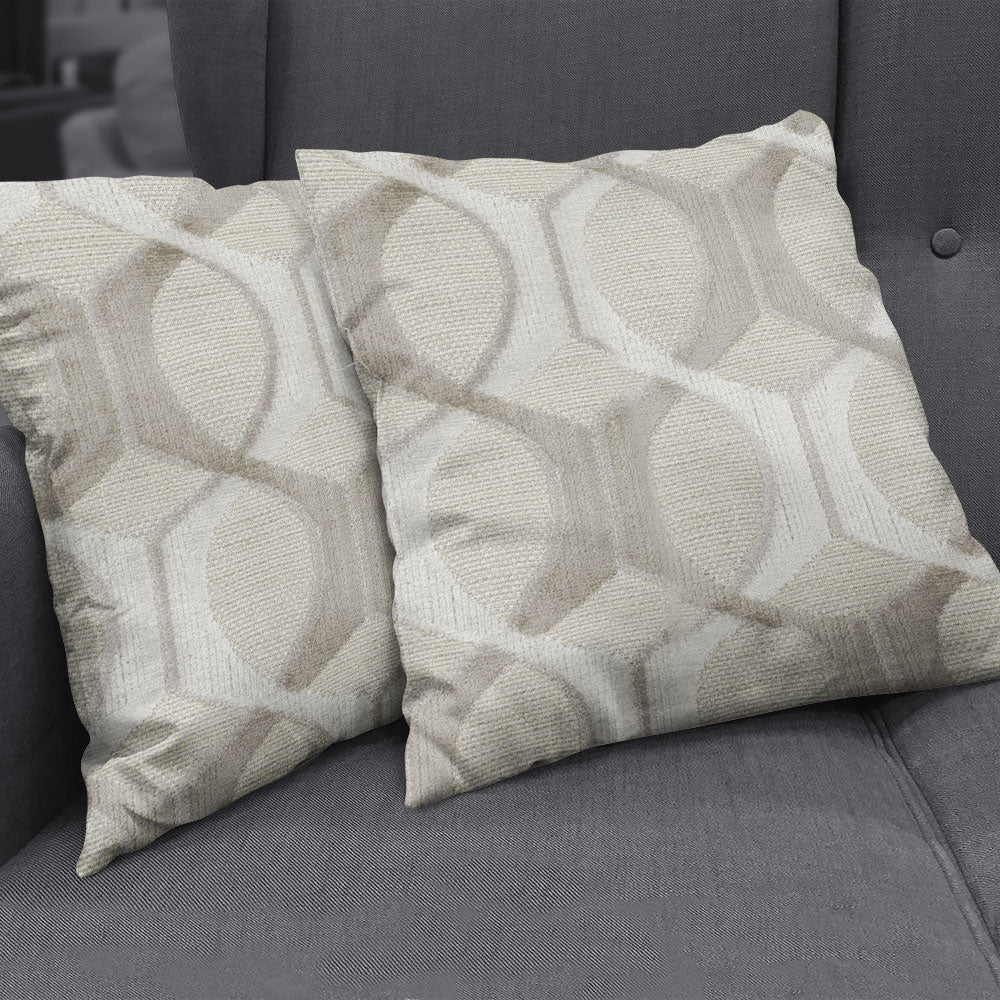Two beige textured throw pillows with a repeating circular geometric pattern on a dark grey sofa.