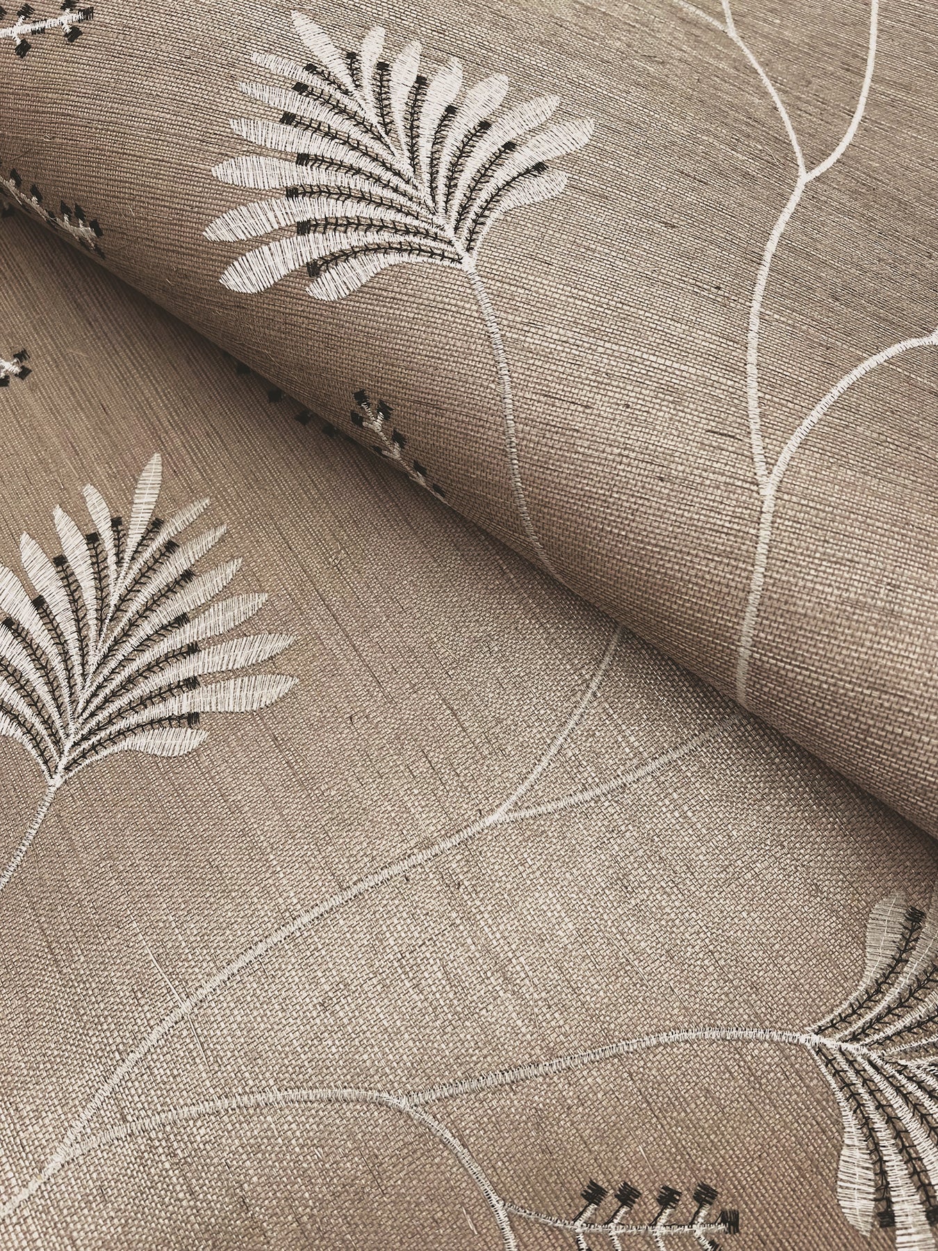 Astoria Laelynn wallpaper MX9607 in Taupe — embroidered botanical columns in metallic silver and charcoal threads over a sisal grasscloth base, giving depth and texture to a neutral taupe ground, ideal for luxury and nature‑inspired interiors.