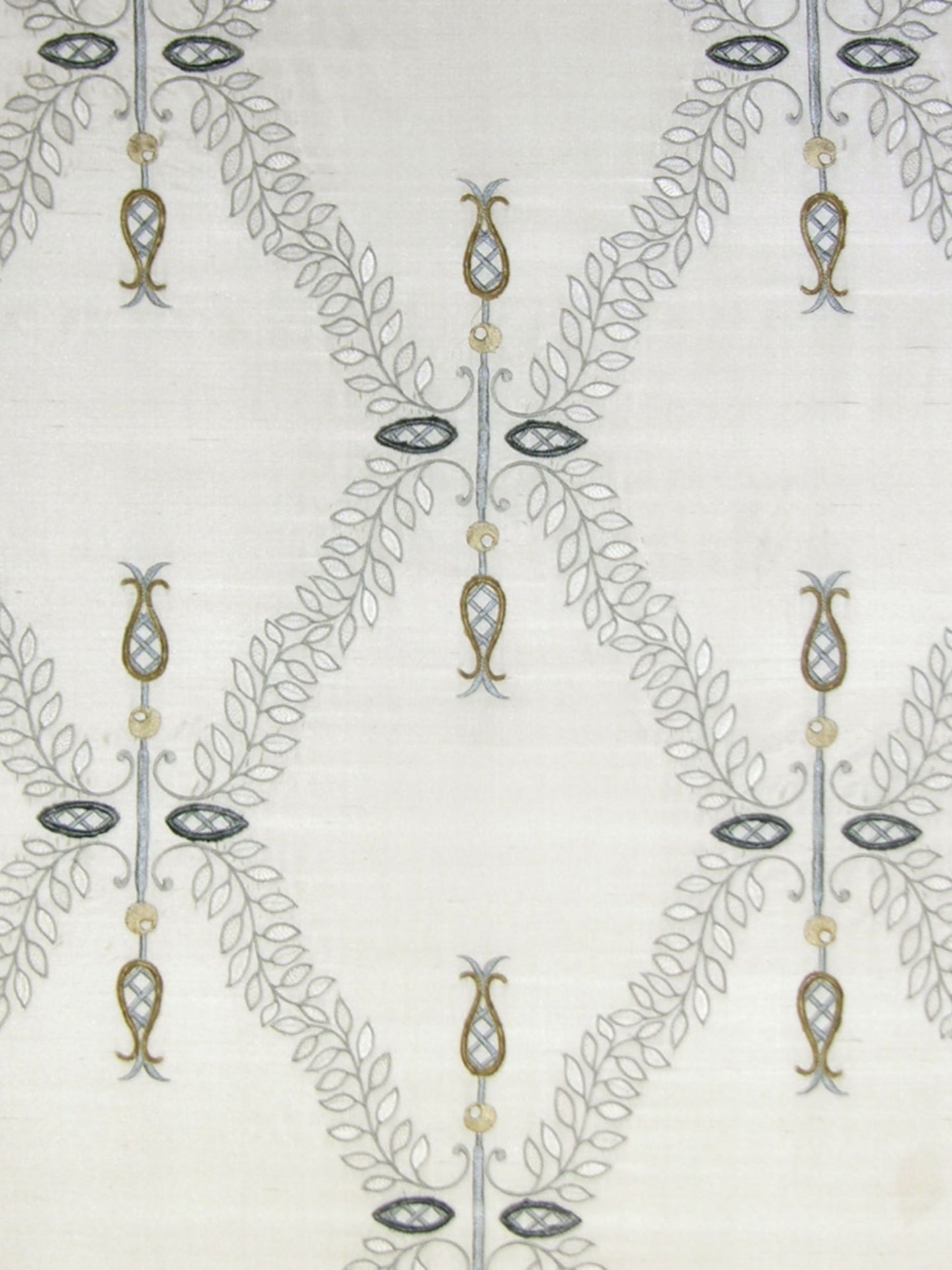 Light neutral linen-like fabric with repeating grey vine lattice forming diamonds; gold beads and navy oval pendants.