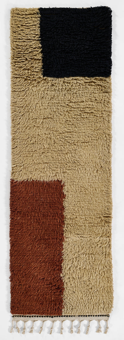 Color-block shag rug with beige field, black square top, rust panel bottom left, and fringed ends.