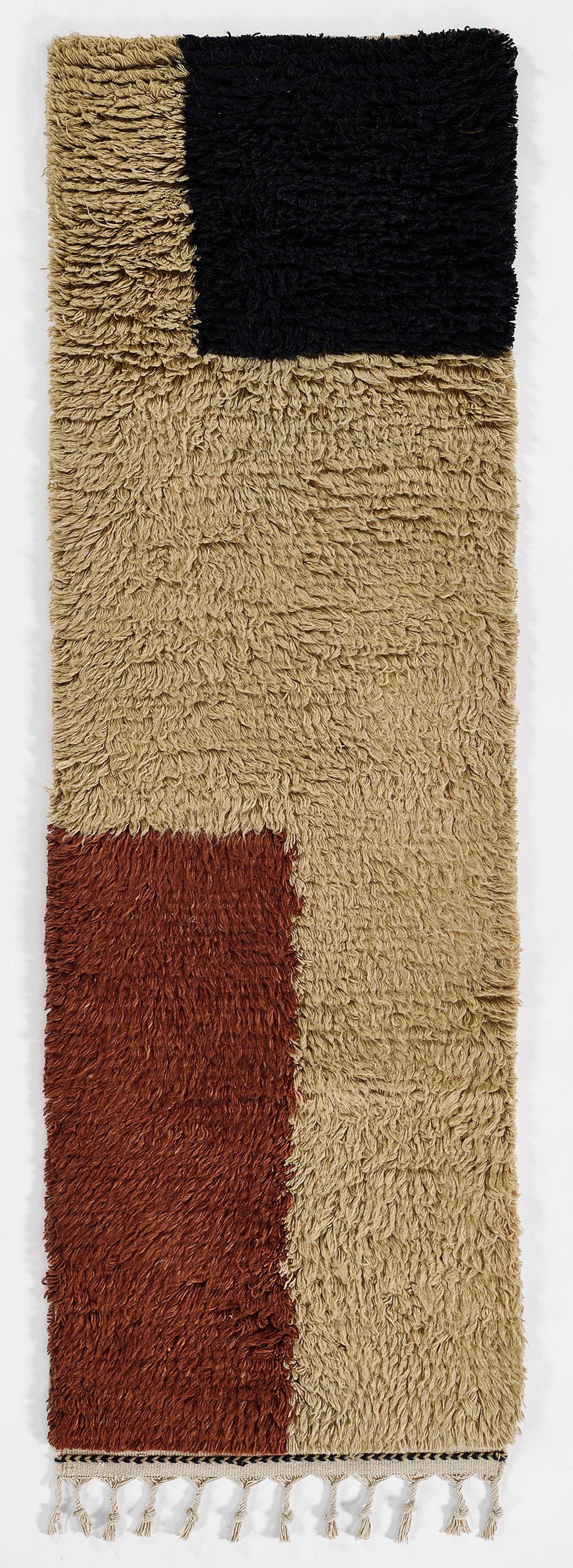 Shaggy color-block rug with tan base, black top-right square, rust bottom-left square, and fringed edges.