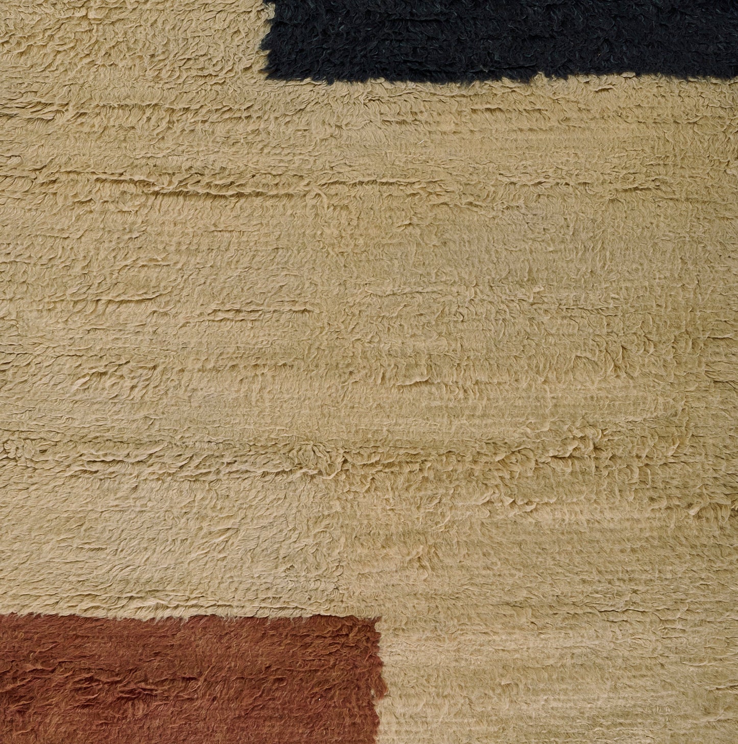 Beige shag rug with dark navy top stripe and rust block accent; thick fluffy pile.