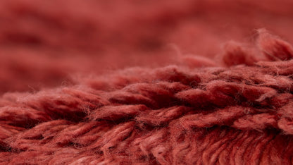 Close-up of red rug fibers with a thick, fluffy pile.