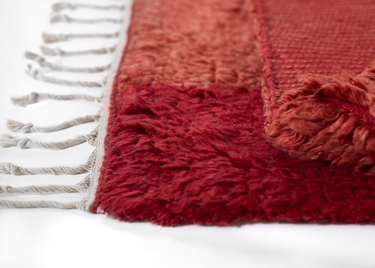 Deep burgundy shag rug with white fringe along one edge and plush fluffy pile.