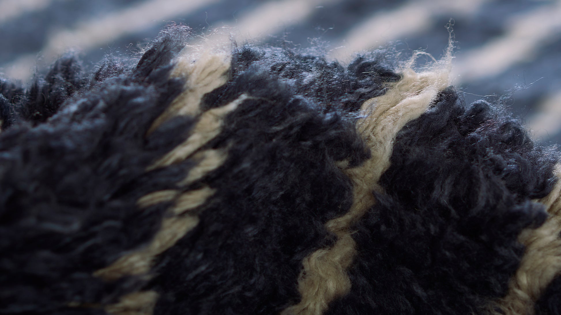 Close-up of black and tan boucle fibers in a rug with fluffy, curly loop pile.