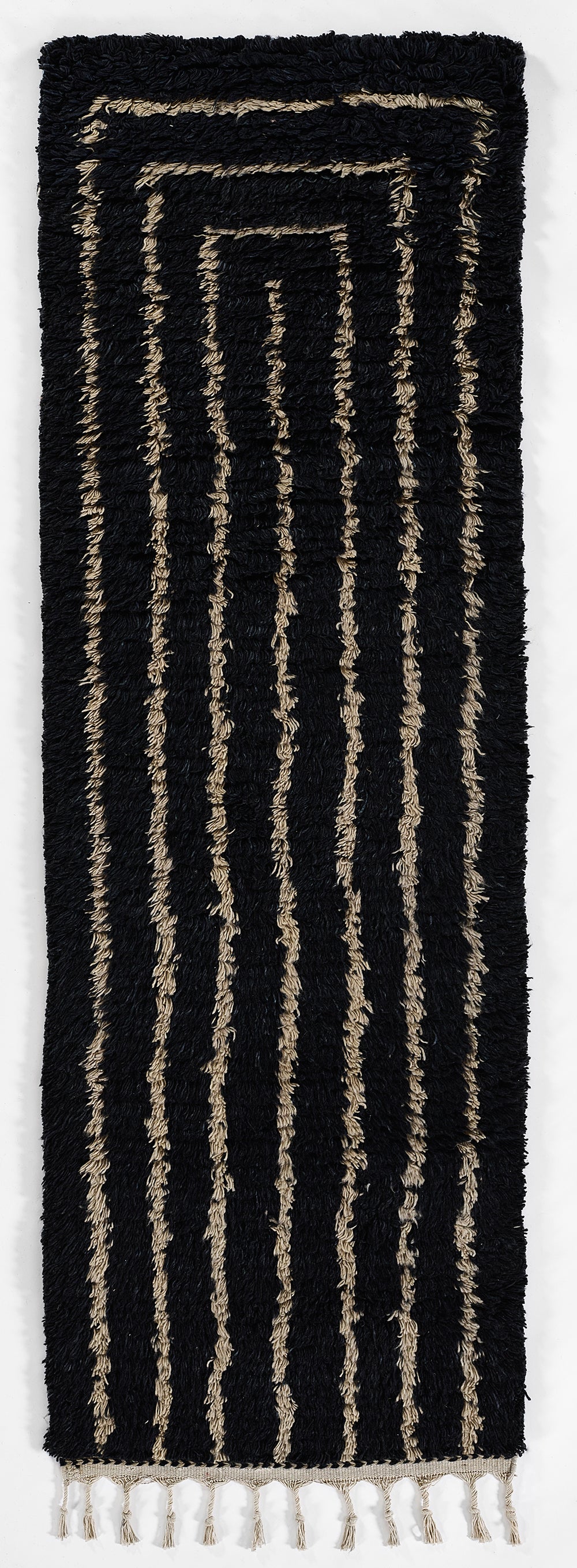 Navy shaggy rug with cream-beige concentric rectangle stripes and beige fringe at the bottom.