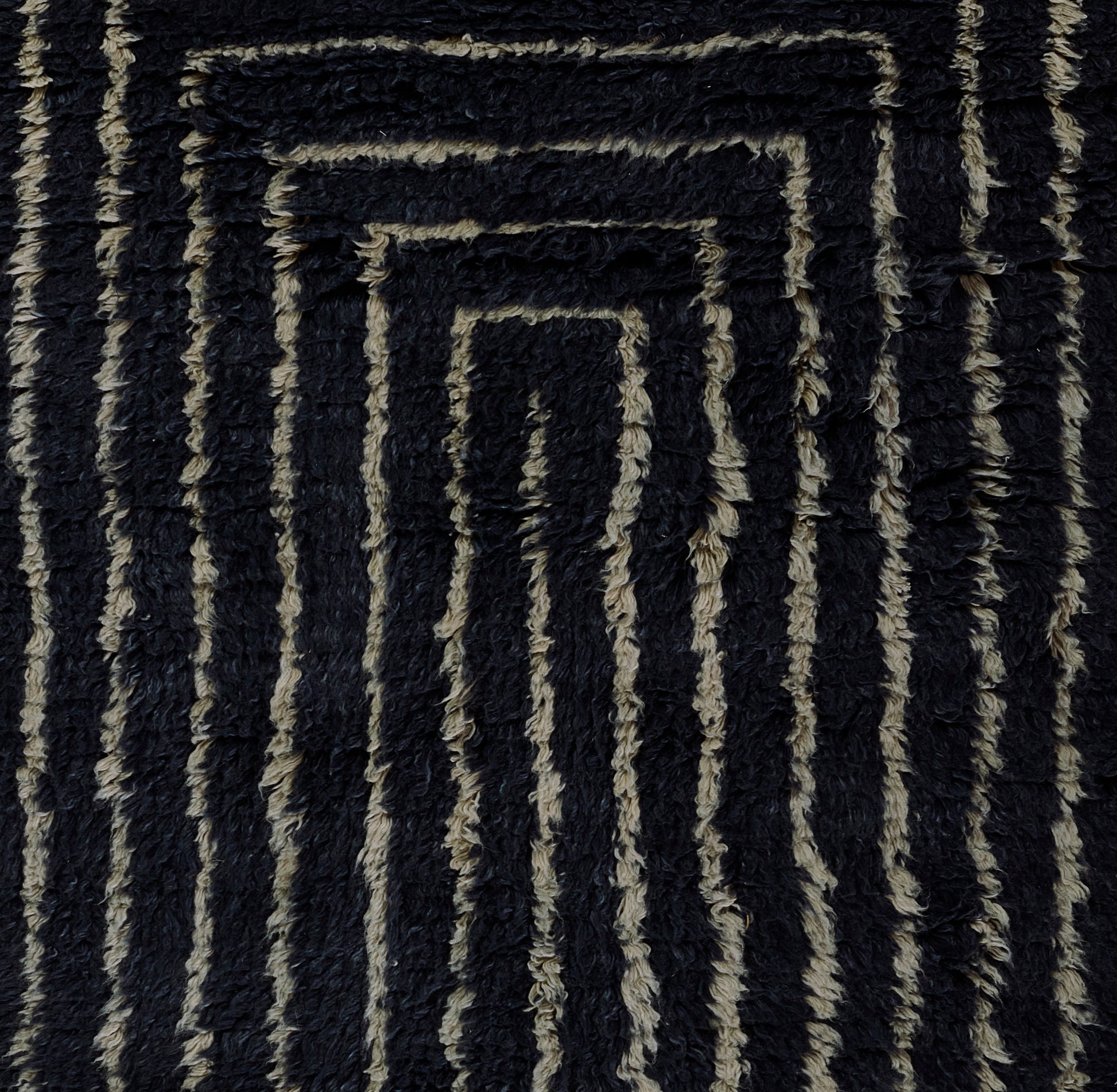 Dark navy shag rug with beige geometric concentric rectangles; plush textured surface for modern living spaces.