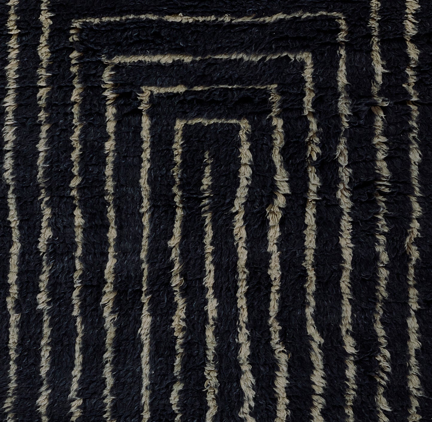 Navy and beige shag rug with raised geometric spiral rectangle pattern; soft tufted texture.