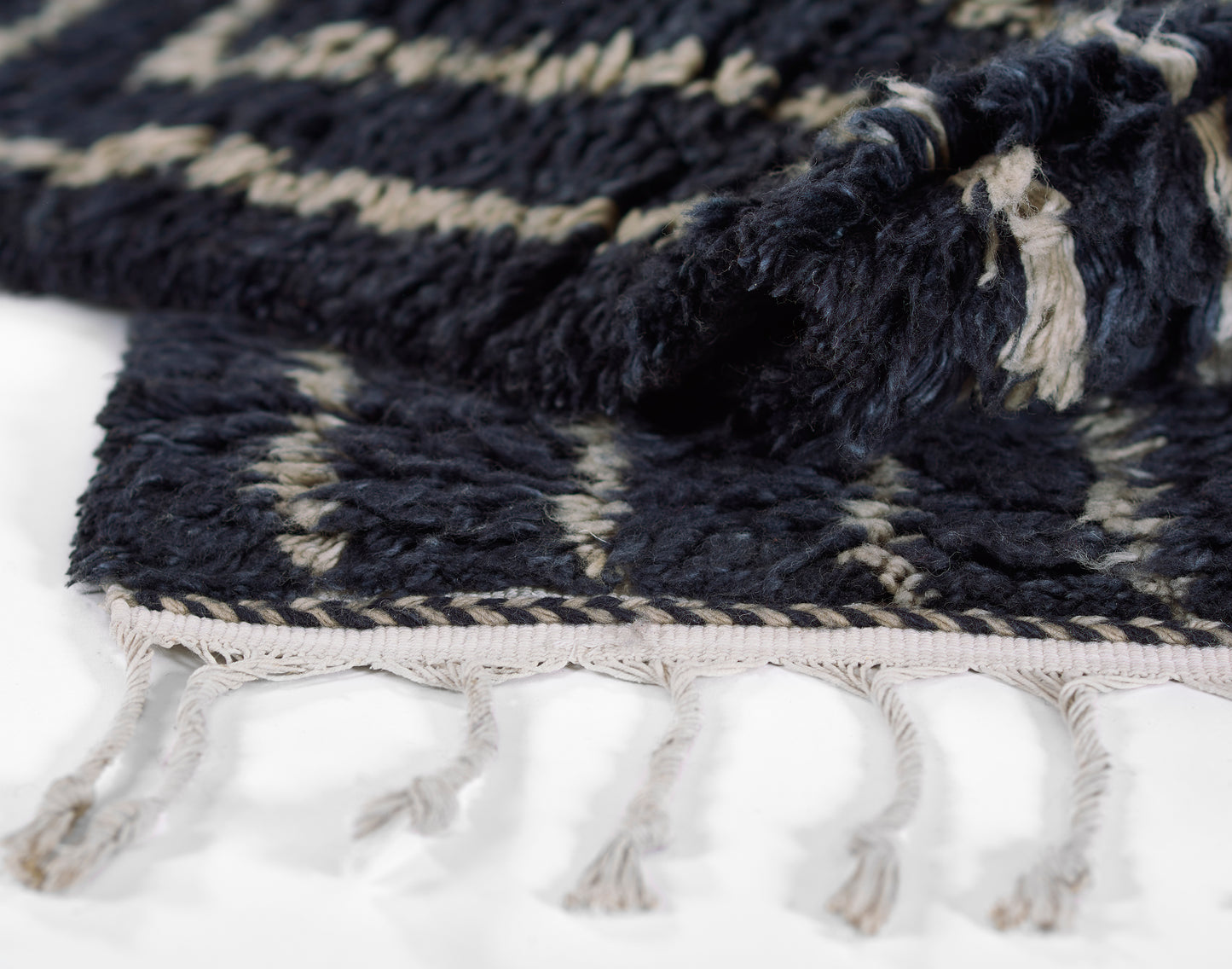 Dark navy woven rug with cream pattern and fringe tassels along edge.