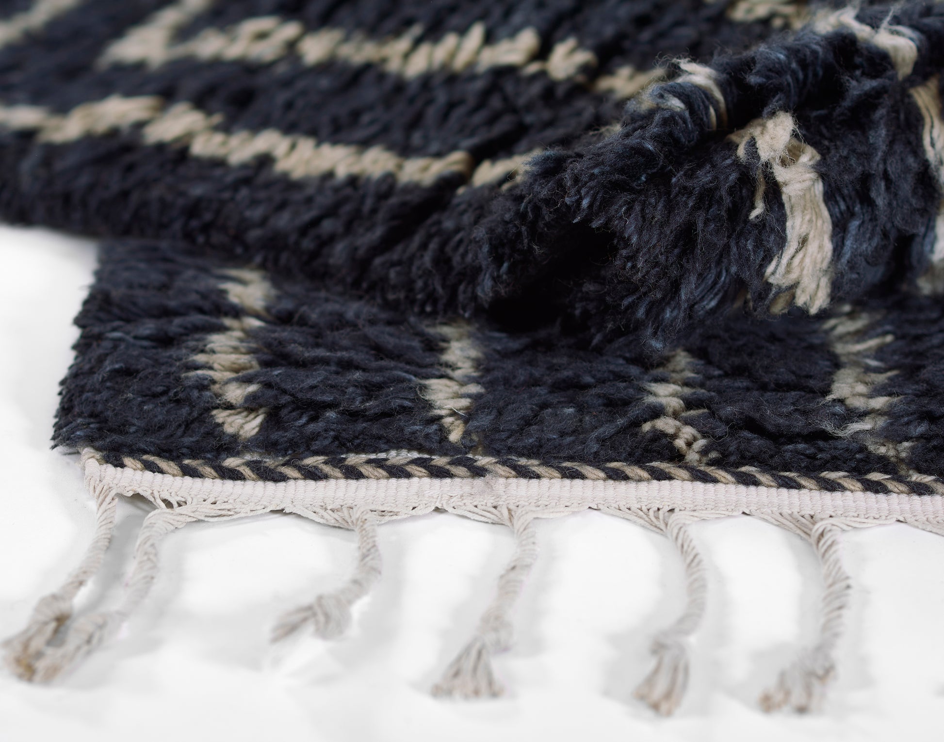 Dark navy woven rug with cream geometric pattern and beige tassel fringe along the edge.