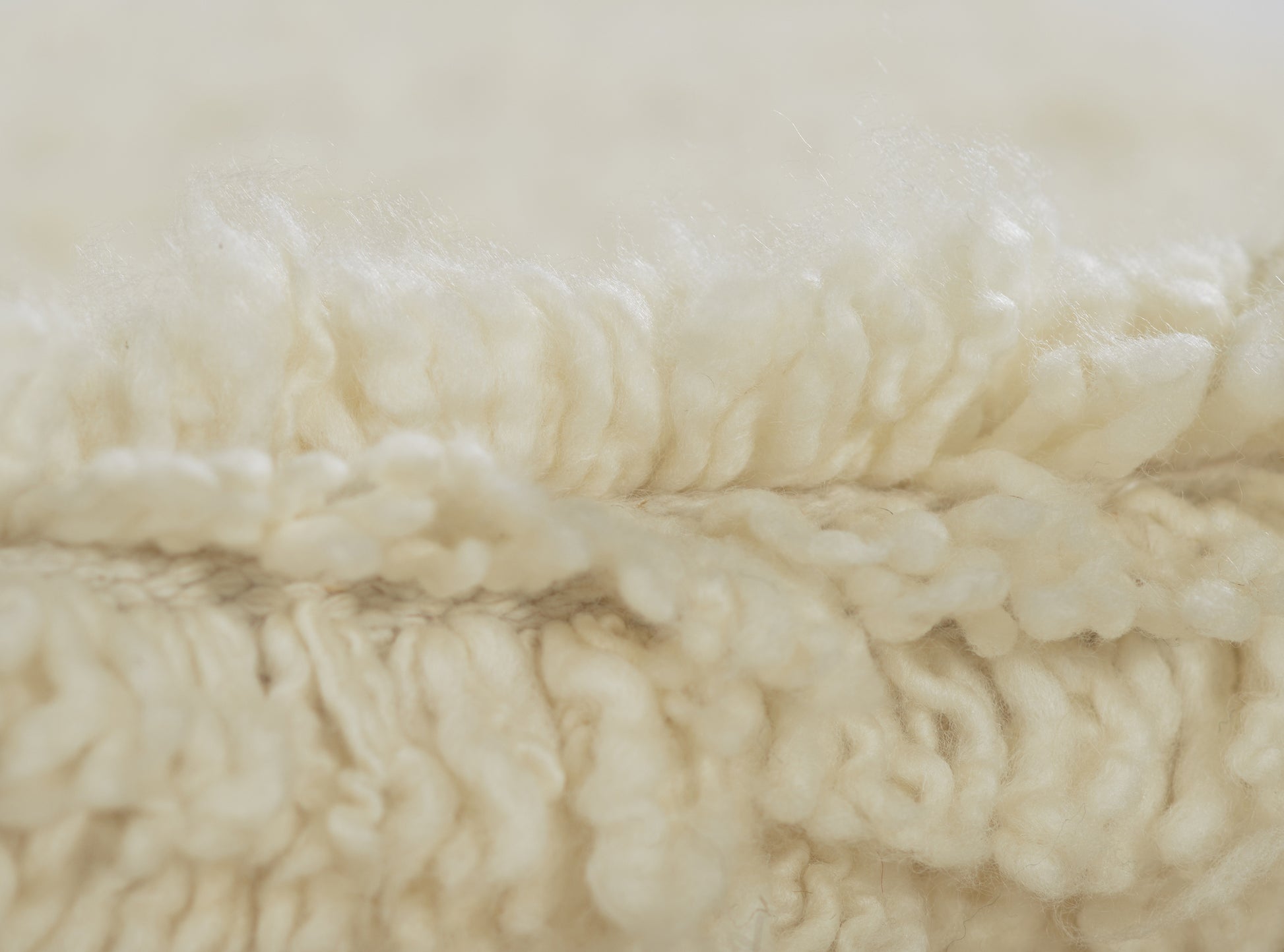 Cream ivory sherpa fleece close-up with fluffy, curly pile, cozy rug texture.