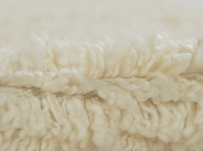 Cream-colored rug close-up showing plush, fluffy pile and soft fibers.