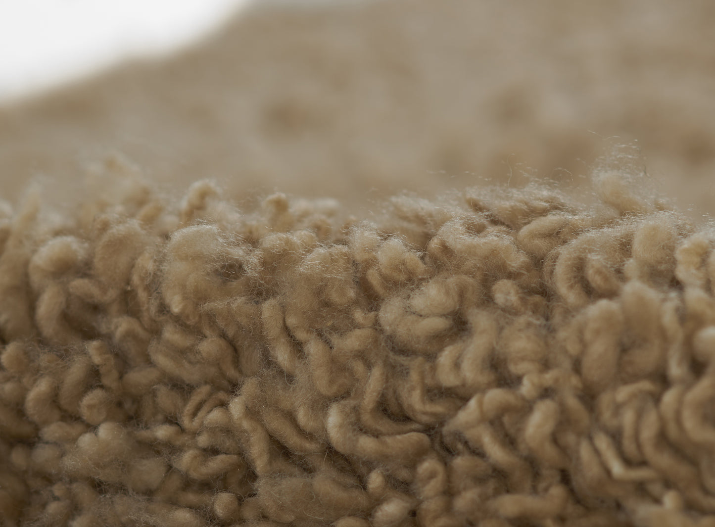 Beige boucle rug close-up with chunky, fluffy wool loops, soft natural texture.