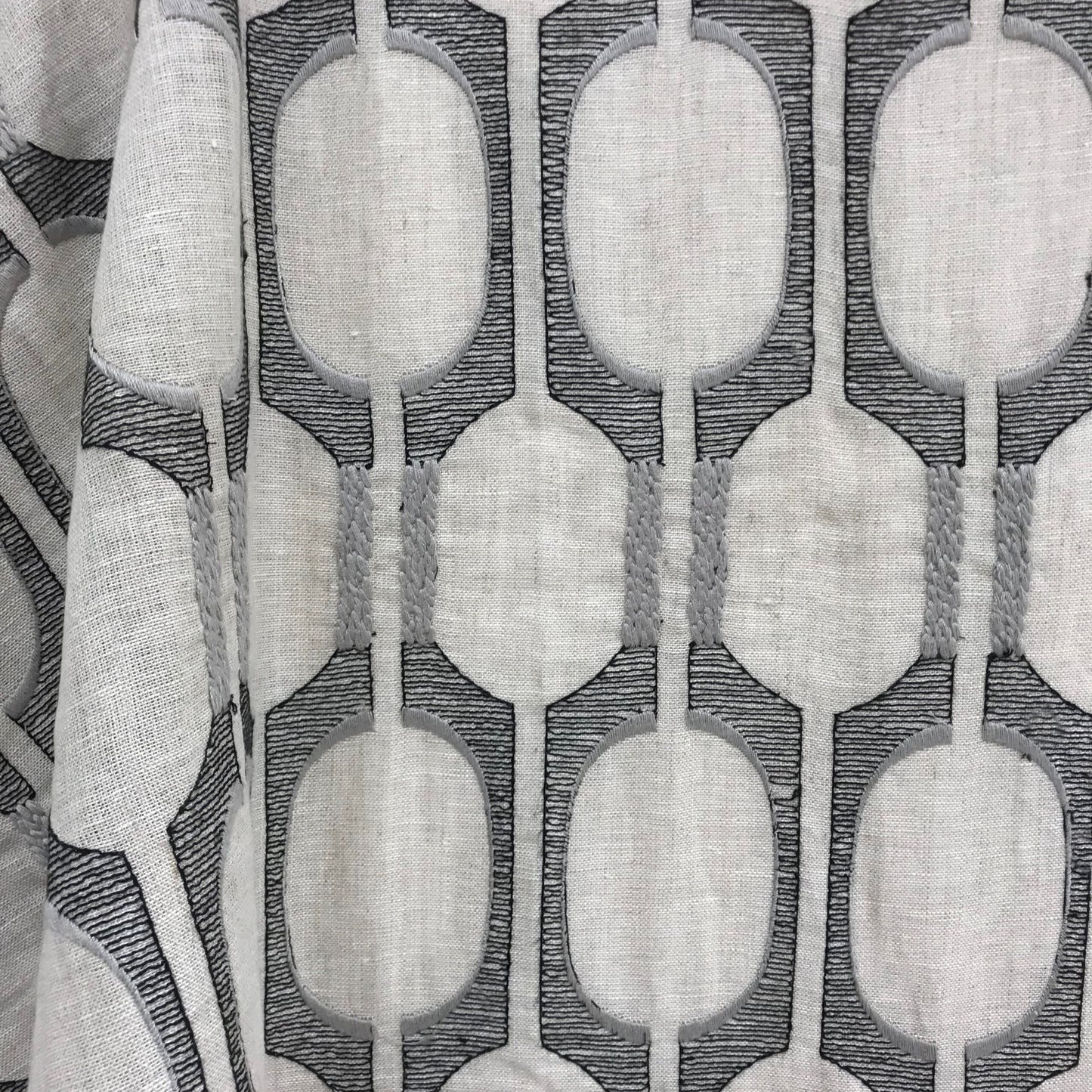Light gray linen-look fabric with a repeating dark-gray oval chain pattern; for drapes or upholstery.