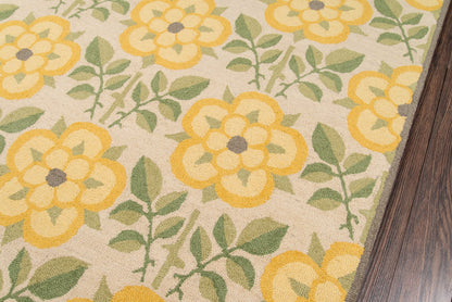Floral area rug with sunny yellow flowers and green leaves on beige backdrop; woven texture near wood floor edge.