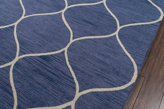 Blue rug with cream curved lattice pattern and plush texture beside dark wood flooring.