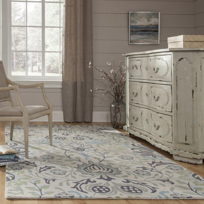 Shabby chic living room with pale blue distressed dresser, beige upholstered chair, and a blue floral area rug.