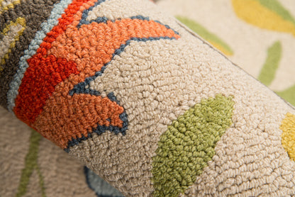 Close-up of a tufted rug with beige base and bright multicolor geometric leaf/flower motifs in orange, green, blue, and red.