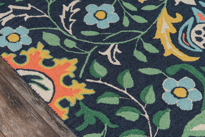 Navy floral rug with blue flowers, green leaves and yellow/orange accents; corner on a wooden floor.