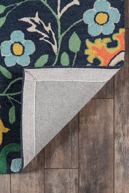 Navy floral rug with turquoise flowers and yellow centers, green leaves; folded corner shows light gray herringbone backing on wood floor.