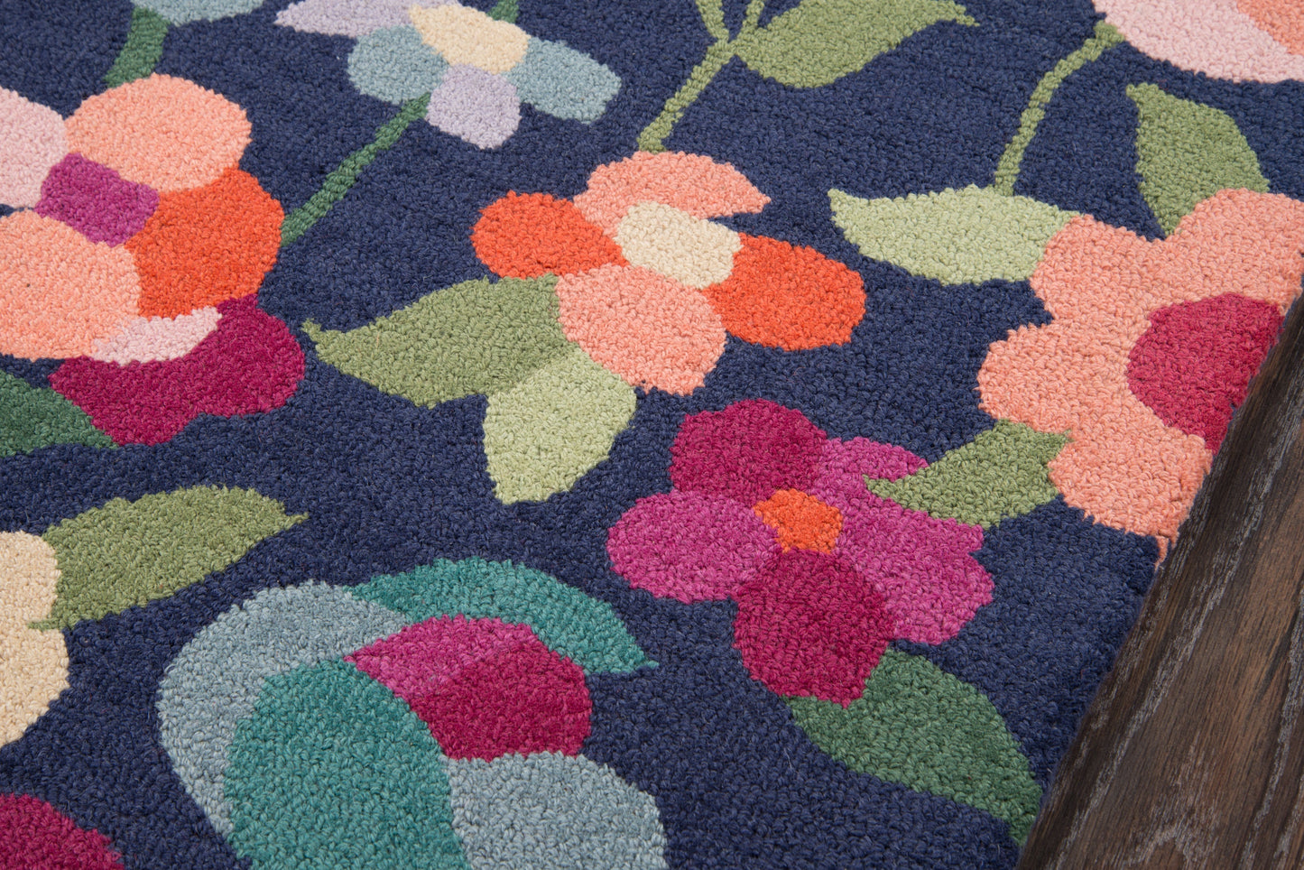 Navy shag rug with vivid pink, peach and coral flowers and green leaves in a plush floral pattern.