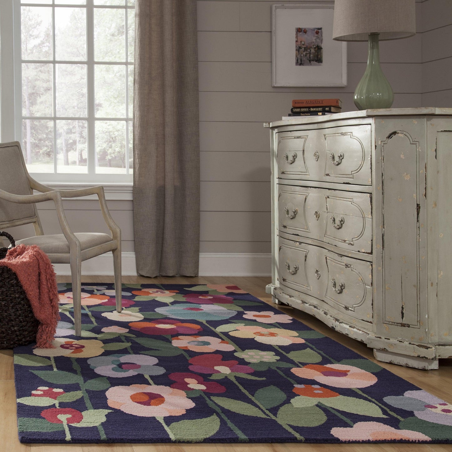 Navy floral rug (2' x 3') on a cozy cottage-style floor, with a beige chair and a distressed pale-blue dresser nearby.