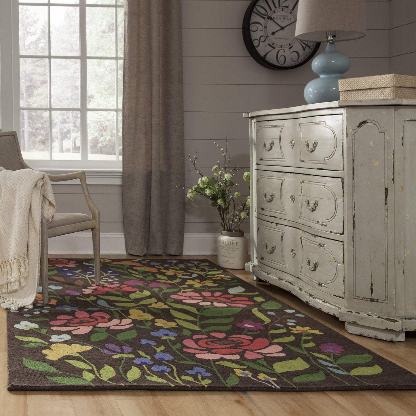 4' x 6' rug with a multicolor floral pattern on pale blue, in a cozy living room with a chair, plant and clock.