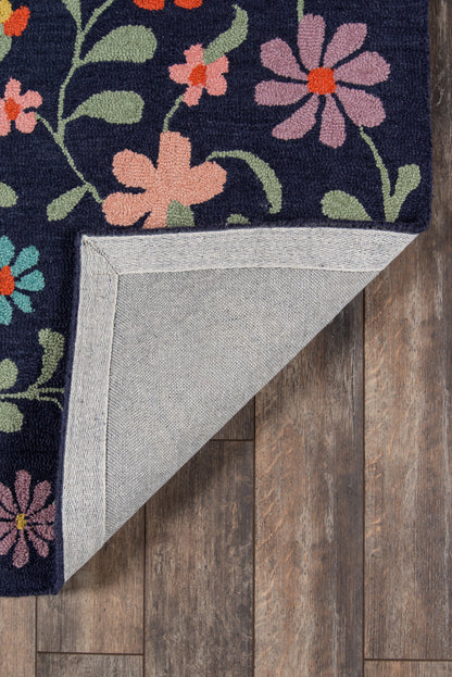 Navy floral area rug with pink and peach flowers and green leaves; folded corner shows light gray back on wood floor.
