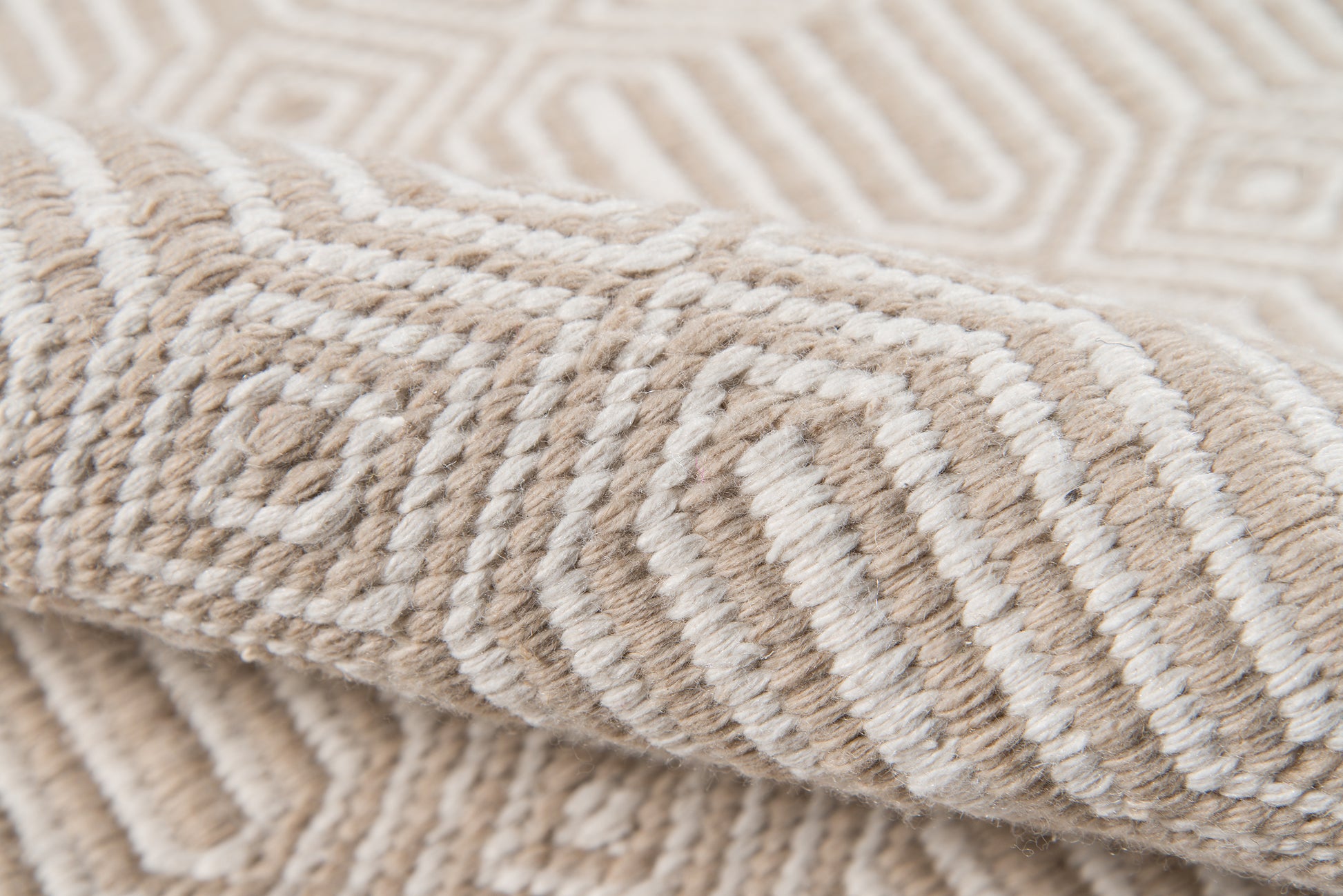 Beige and off-white geometric woven rug with thick textured pile and swirling ring motif.