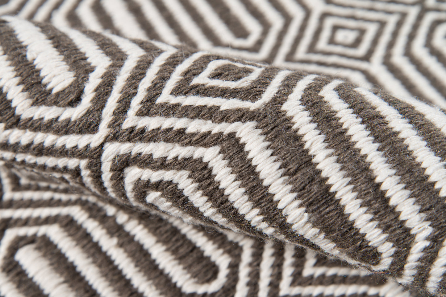 Brown and white geometric knit throw blanket with maze-like pattern and soft wool texture