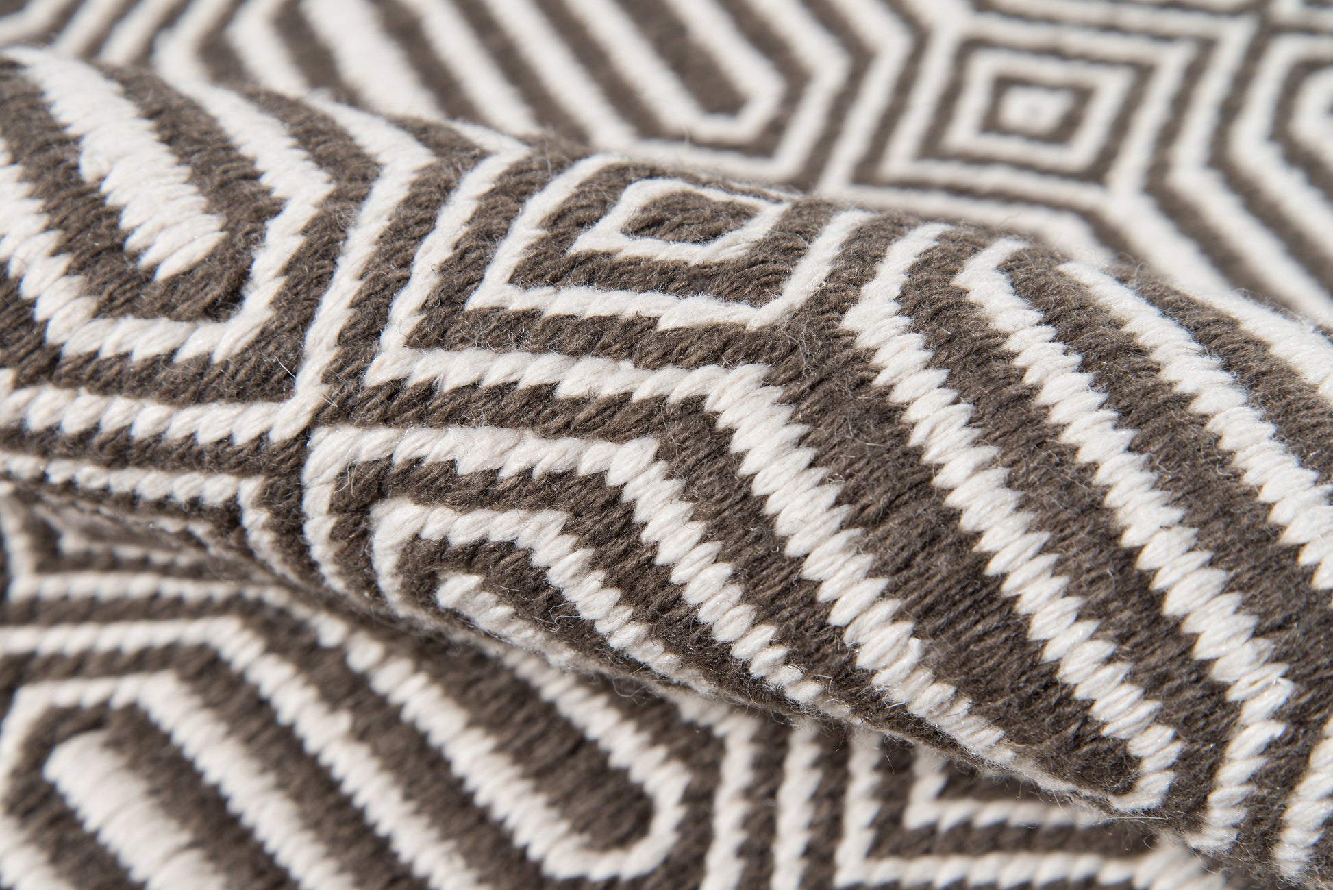 Brown and white geometric knit throw blanket with maze-like pattern and soft wool texture