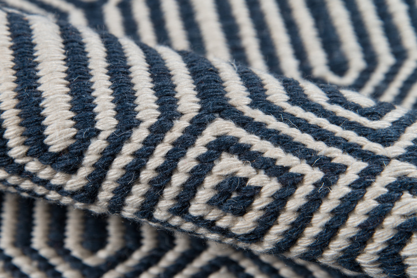 Close-up of Newton wool throw in navy and ivory with a bold geometric maze pattern.