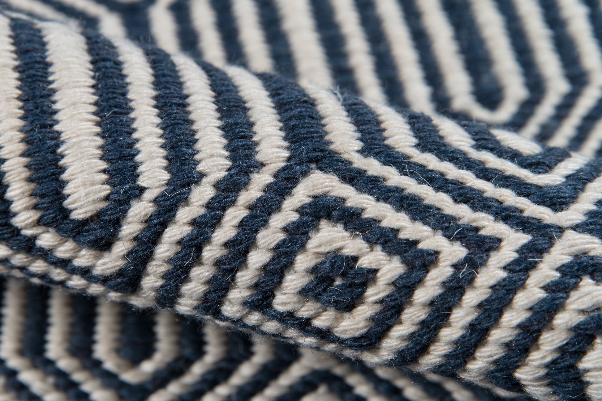 Close-up of Newton wool throw in navy and ivory with a bold geometric maze pattern.