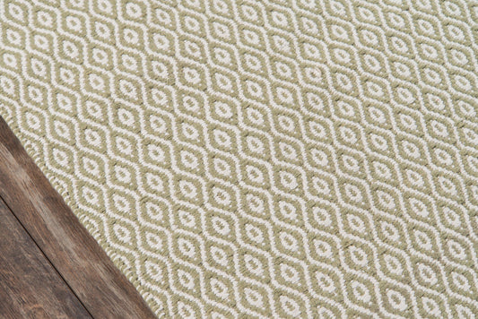 Olive-green and cream geometric diamond rug on dark wood floor with woven texture; modern contemporary style.