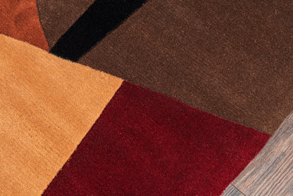 Color-block round rug with orange, tan, red & brown panels and a black stripe on wood floor.