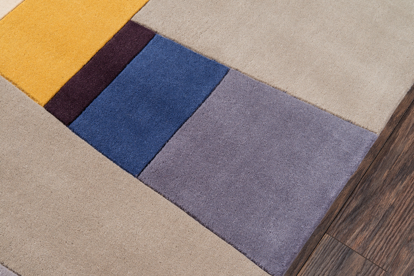 Modern patchwork rug runner with yellow, burgundy, blue, lavender & gray blocks on warm beige flooring.