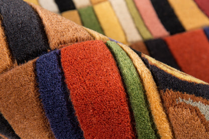 Macro view of a multicolor striped rug with fuzzy pile in orange, red, green, blue, brown and black.