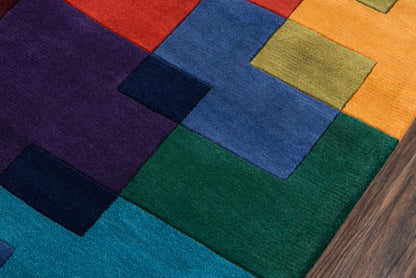 Colorful geometric patchwork runner rug with multicolor squares (red, orange, yellow, green, blue, purple) on wood floor.