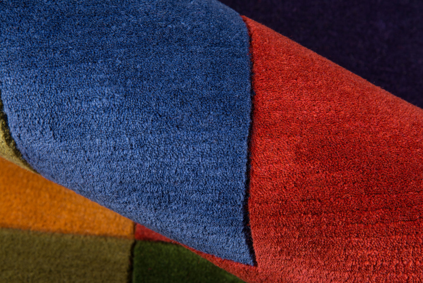 Soft plush patchwork textile with blue and red panels, orange and green blocks, velvety terry texture.