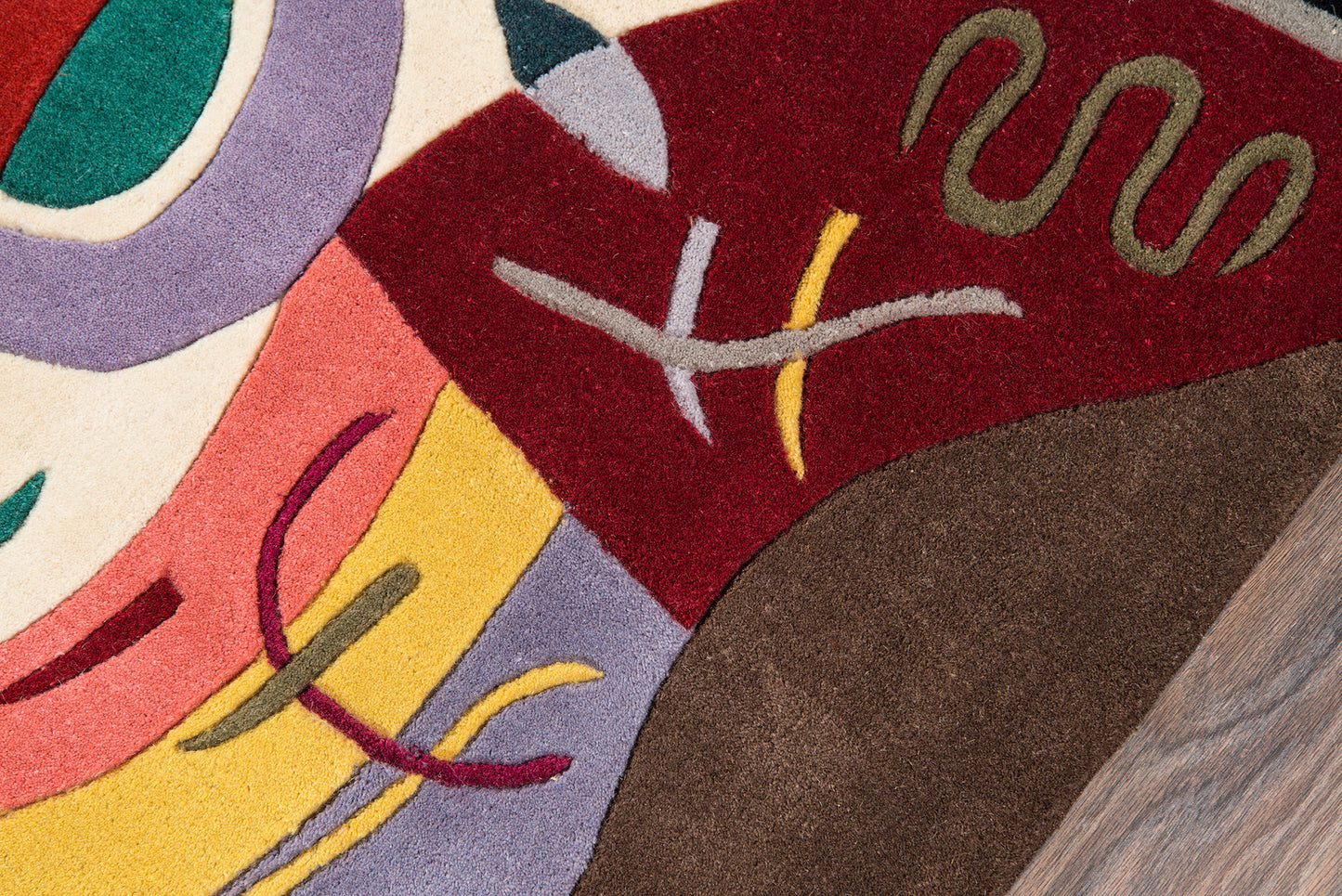 Abstract multicolor area rug with bold geometric shapes in maroon, yellow, lavender, pink, teal and brown.