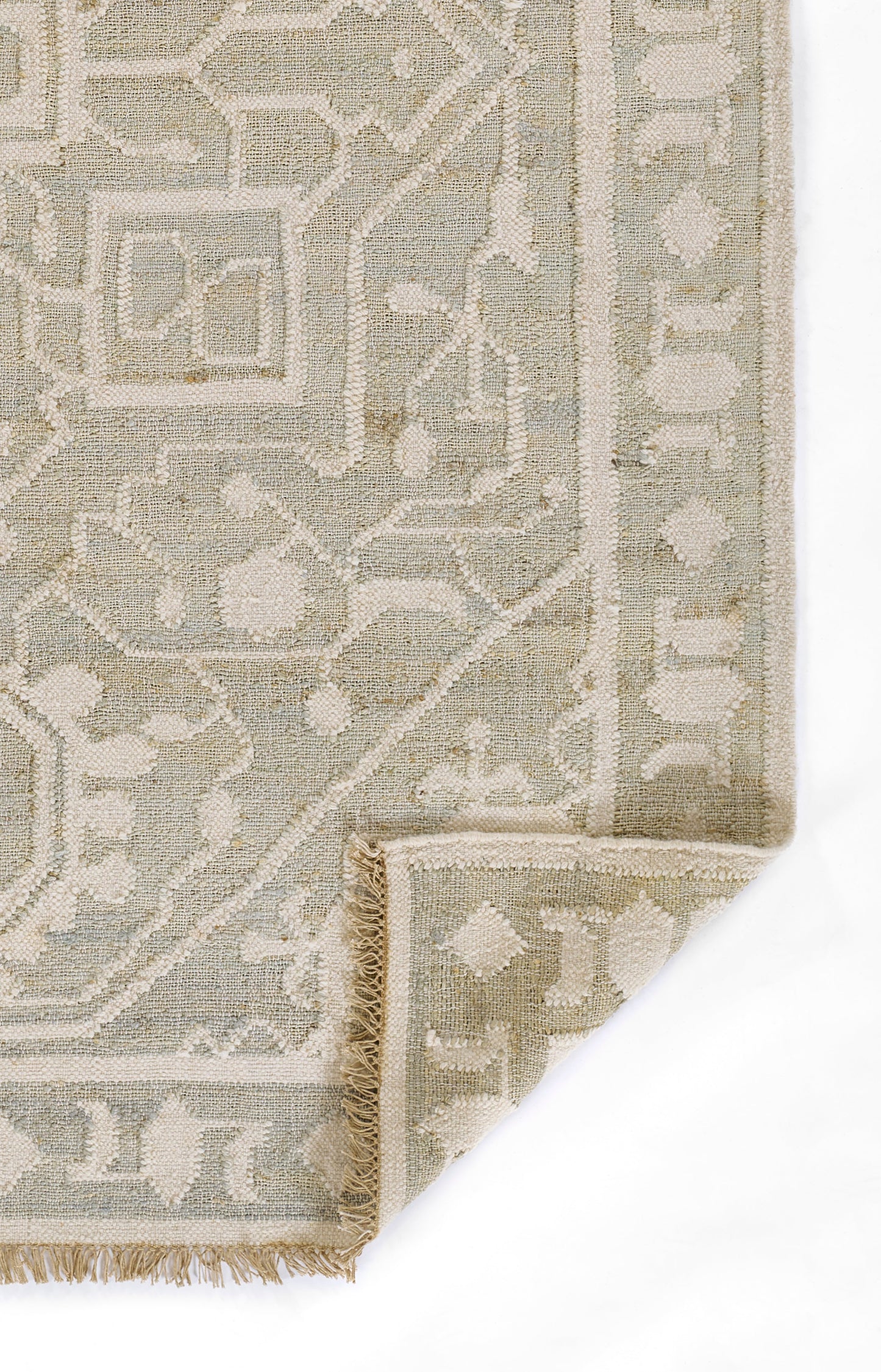 Muted beige and ivory woven rug with geometric/arabesque border, fringe edge and folded corner