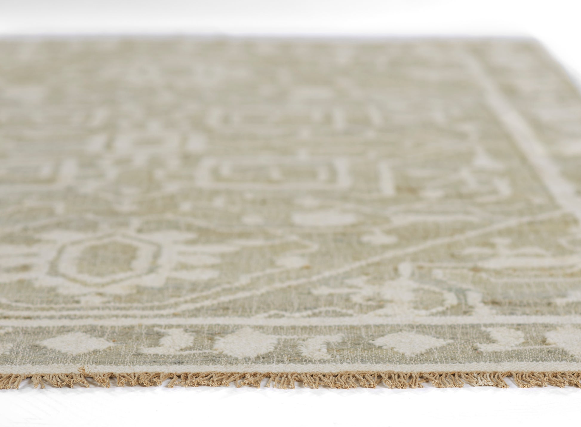 Beige and cream oriental rug with subtle blue accents, geometric floral pattern and fringe along the edge.