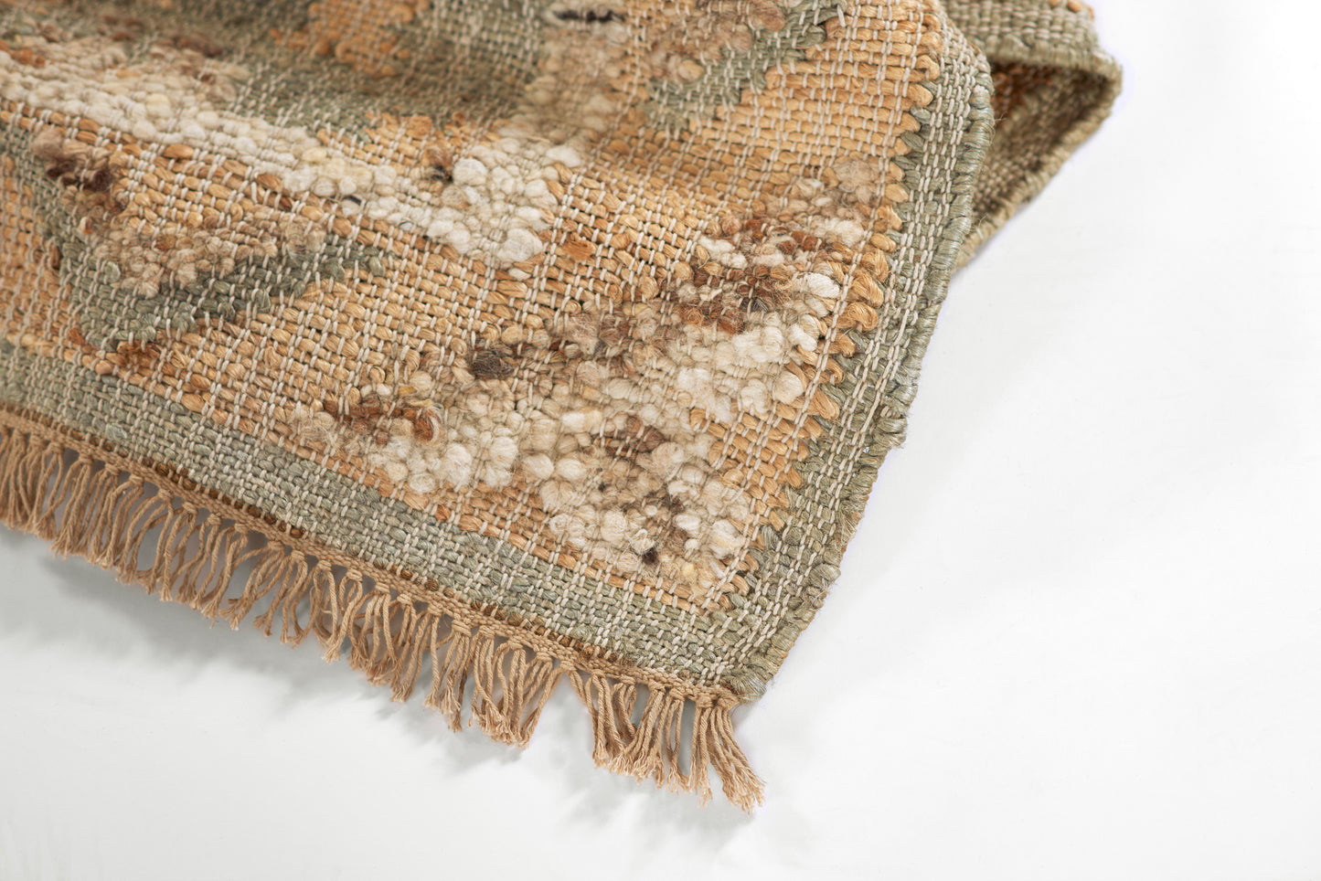 Muted green, beige, and tan woven rug with chunky texture and fringe; boho kilim-style.