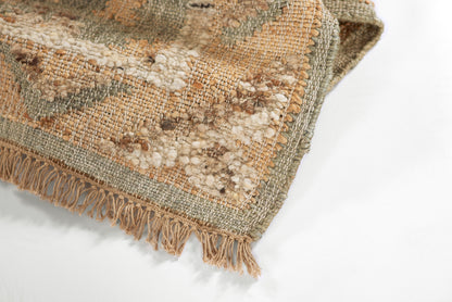 Muted green, beige, and tan woven rug with chunky texture and fringe; boho kilim-style.