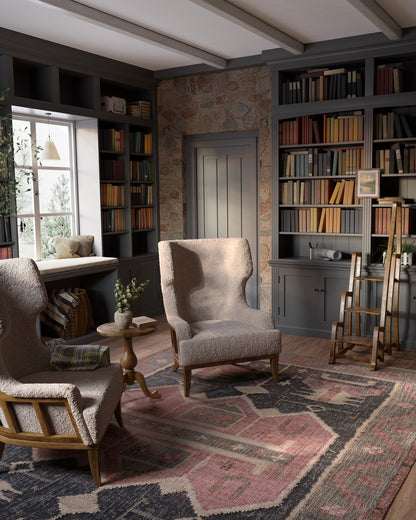 Cozy library nook with dark gray shelves, stone doorway, two beige boucle chairs, round wood table, and a 2' x 8' runner rug.