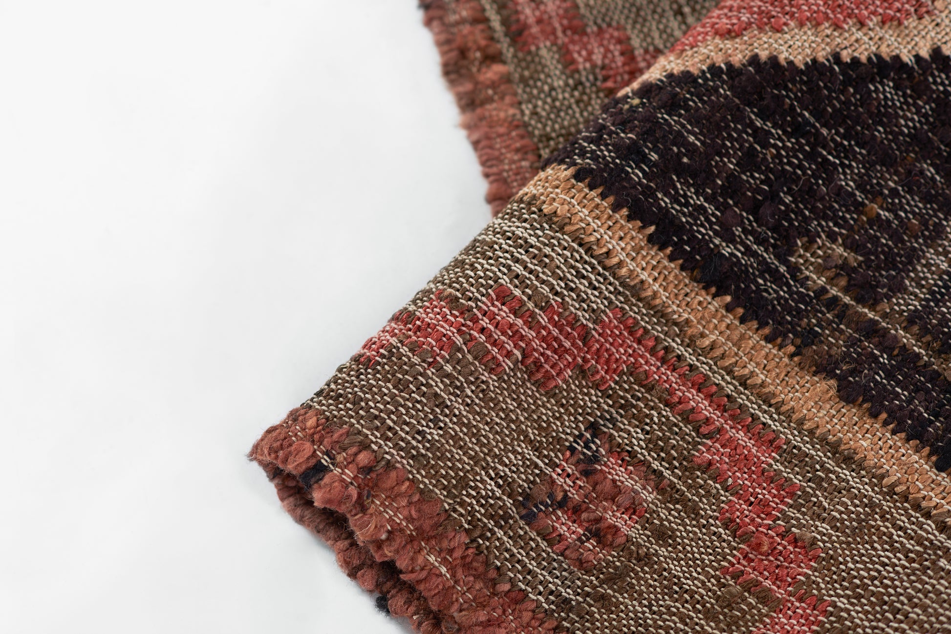 Close-up of rustic woven rug with red, tan and brown stripes, textured looped yarns and fringed edge, boho style