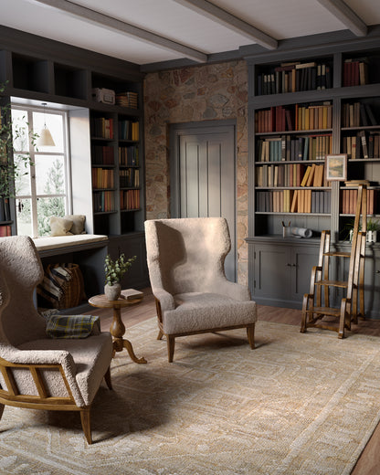 Cozy living room with beige boucle armchairs, round side table, dark gray built-in bookcases, stone wall, and beige rug.